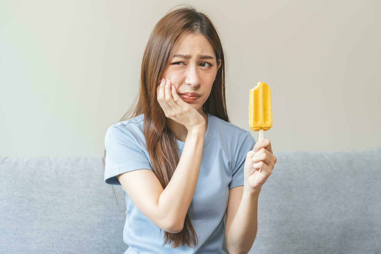 Face expression suffering from sensitive teeth and cold, asian young woman,  girl feeling hurt, pain eating ice cream, lolly. Toothache molar tooth at  home, dental problem isolated on white background. 25133068 Stock